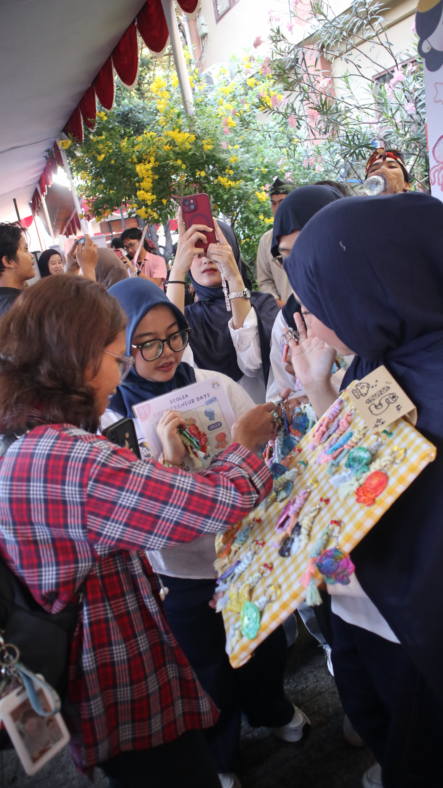 Pengunjung memilih gantungan kunci ramah lingkungan Ecolea yang dibuat dari tutup botol plastik bekas.